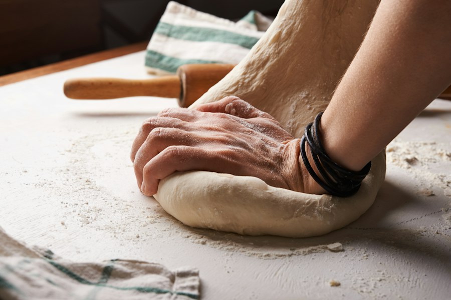 Hands kneading a ball of dough on a floured counter