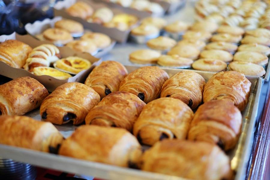 Trays of pastries lined up inside a bakery display case